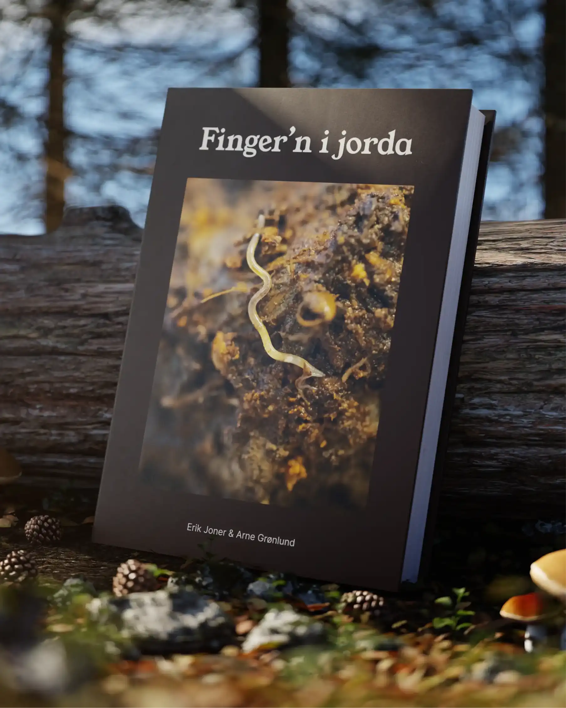 3D-render av boka Finger'n i jorda. I et skandinavisk skog-landskap, står boka oppstilt på bakken foran en liggende trestamme.
